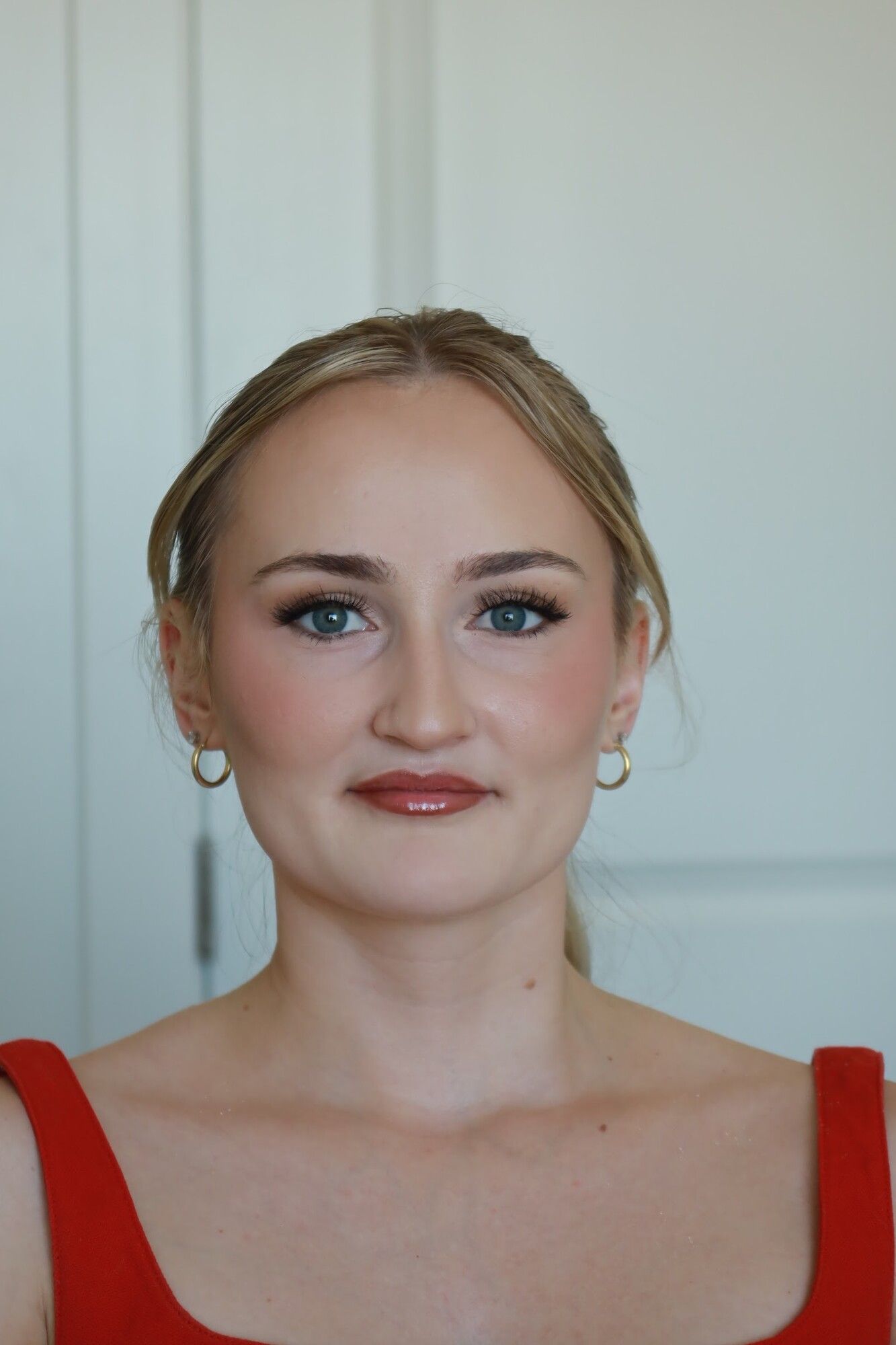 After: the same woman with a sleek low bun and polished soft glam makeup