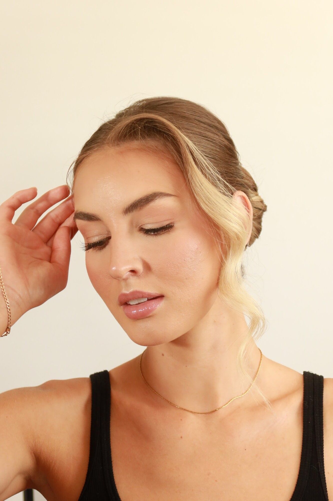 After: the same woman with a sleek low updo, soft pieces at the face and bronzed soft glam