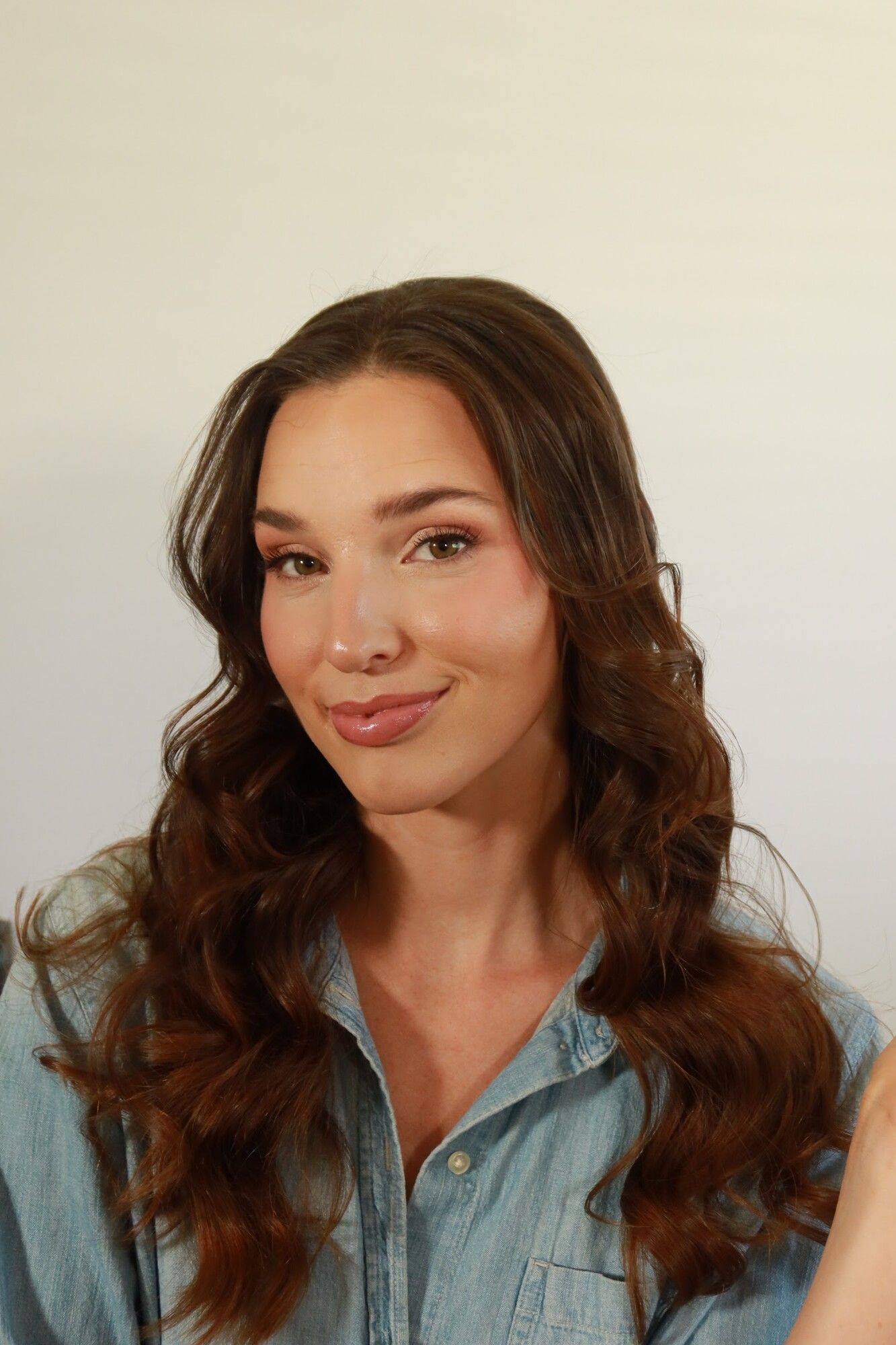 After: the same woman with long bouncy waves and soft glam makeup