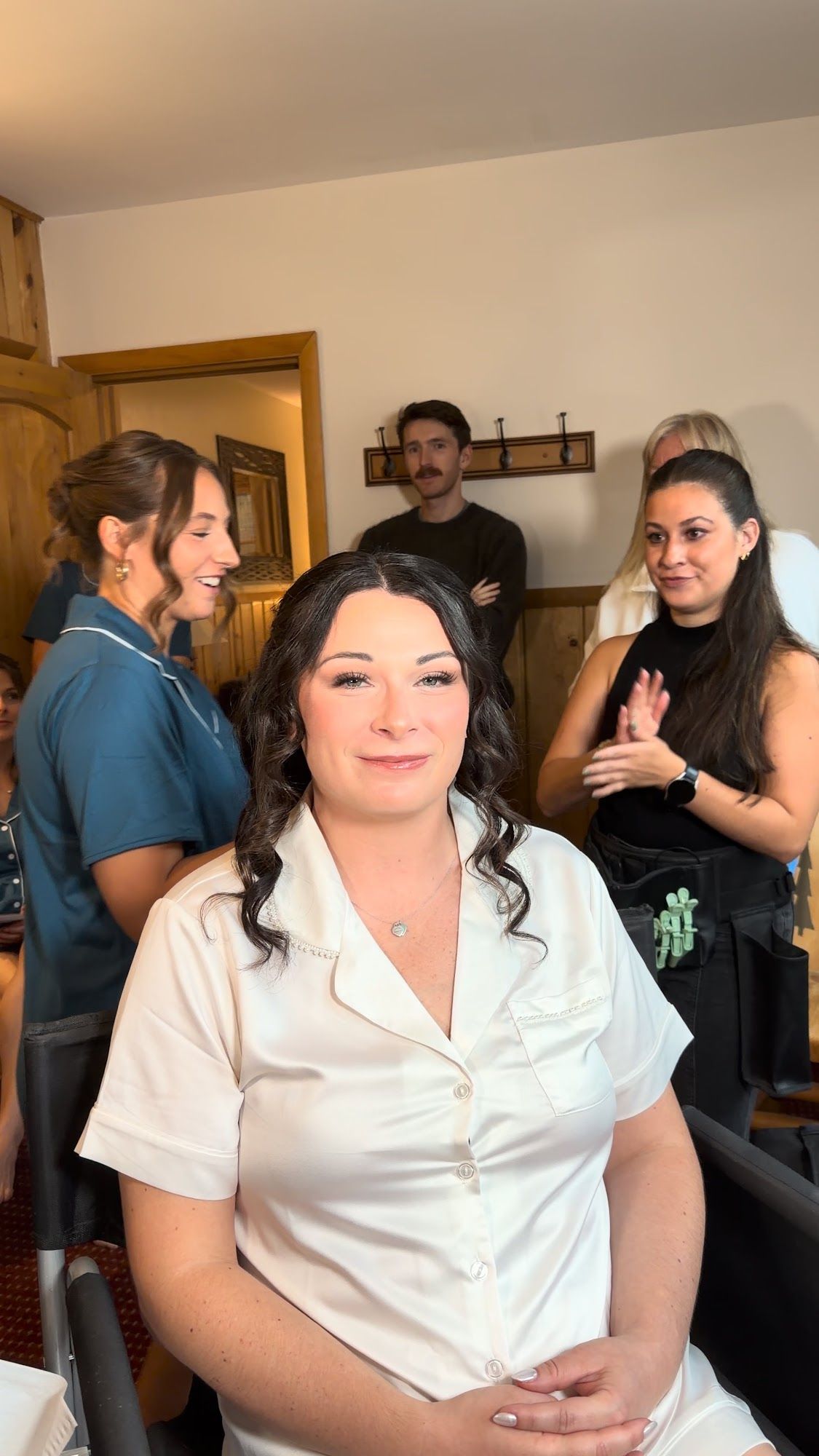 After: the same woman in the chair with finished makeup and soft curls