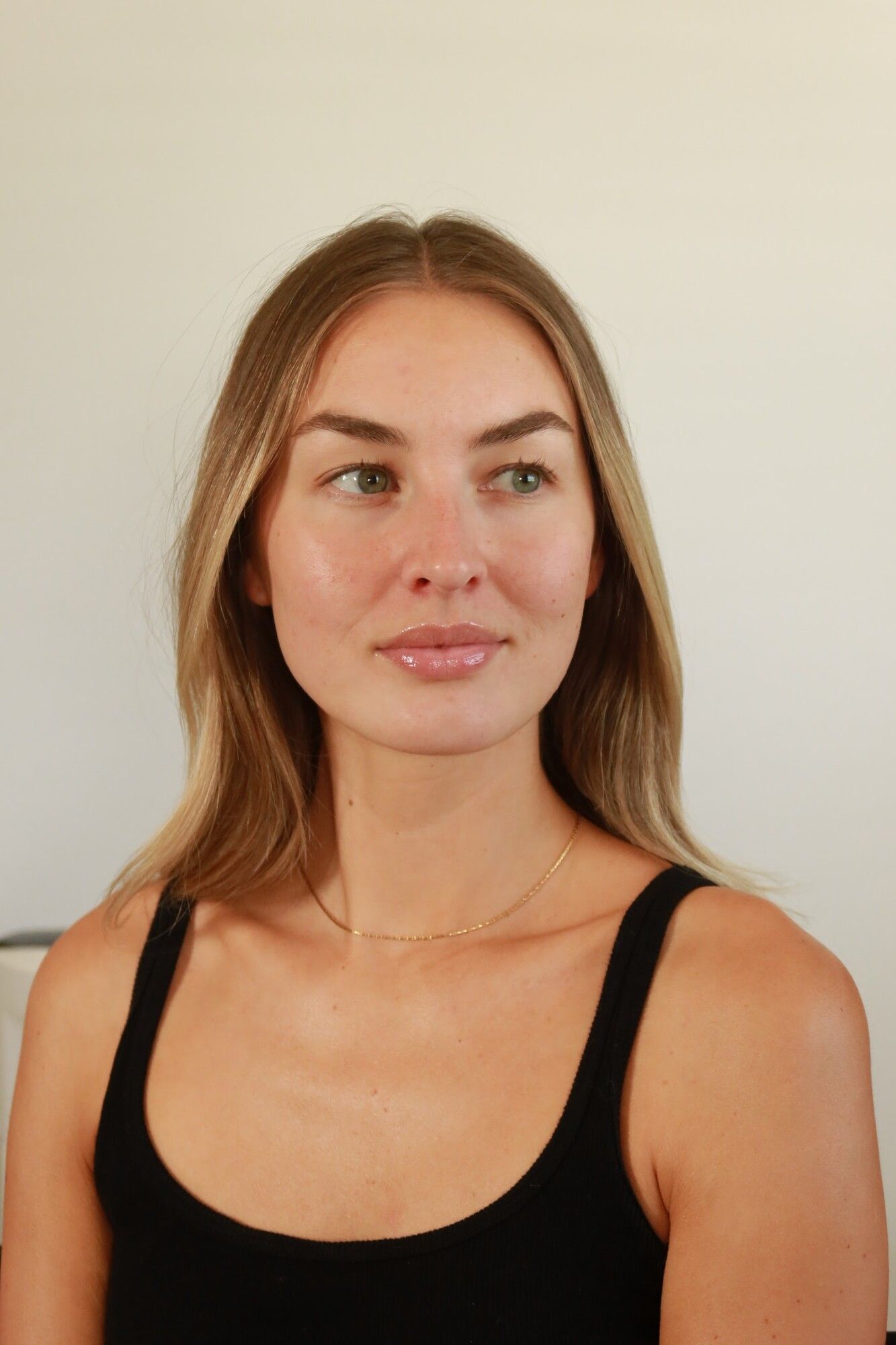 Before: a woman in a black tank top with hair down and bare skin
