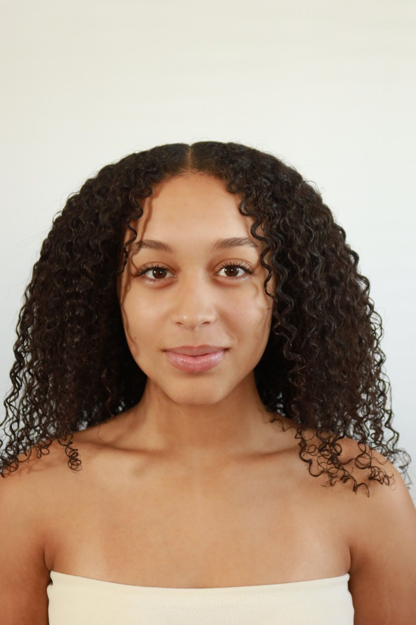 Before: a woman with natural curls and bare skin