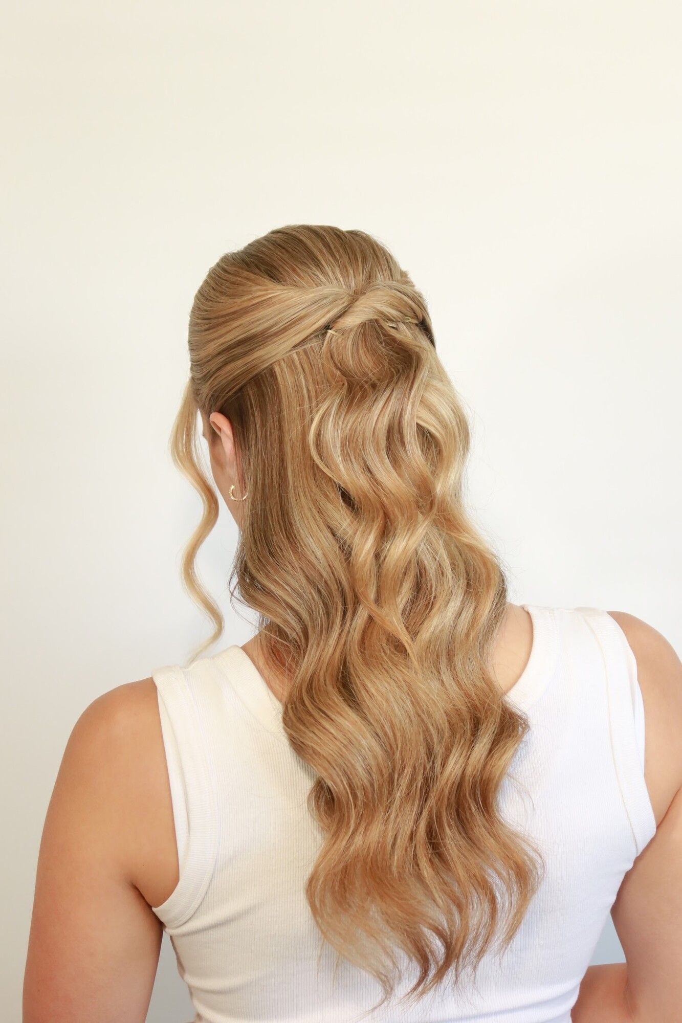 Back view of long blonde hair in polished Hollywood waves, half pinned