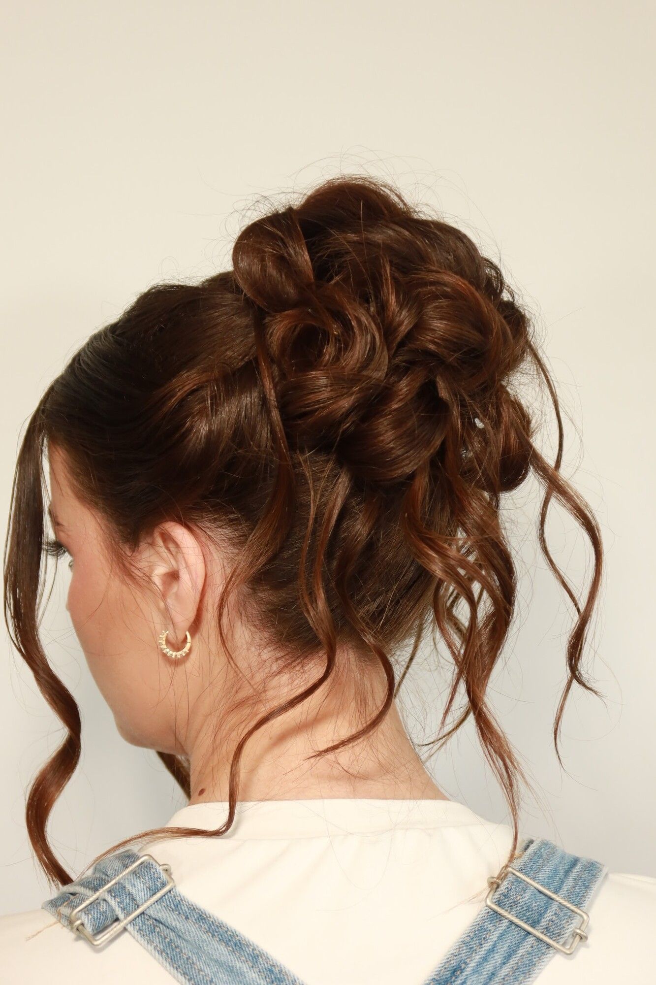 Back view of a textured bridal updo with soft curls left loose