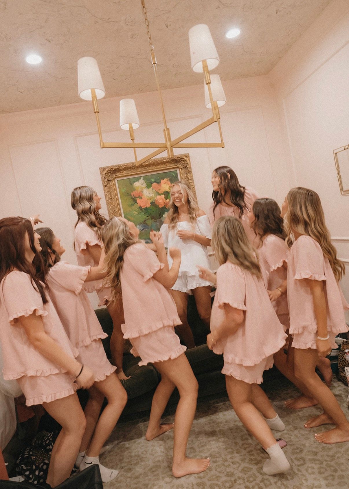 Bridesmaids in matching pink pajamas dancing together in the getting-ready room