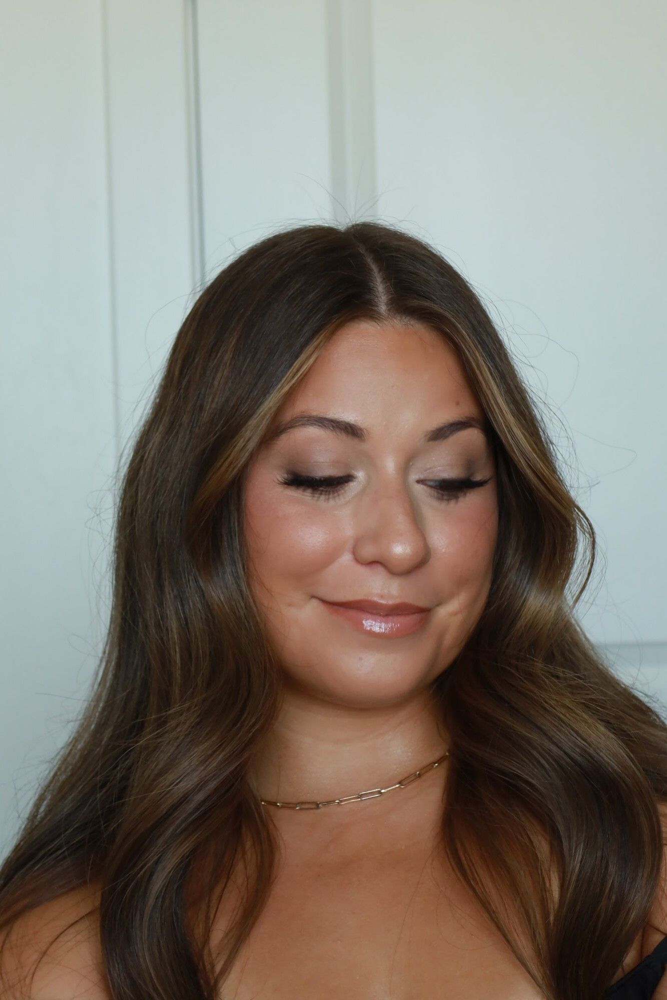 A brunette with long soft waves and a glowing bronzed soft glam finish