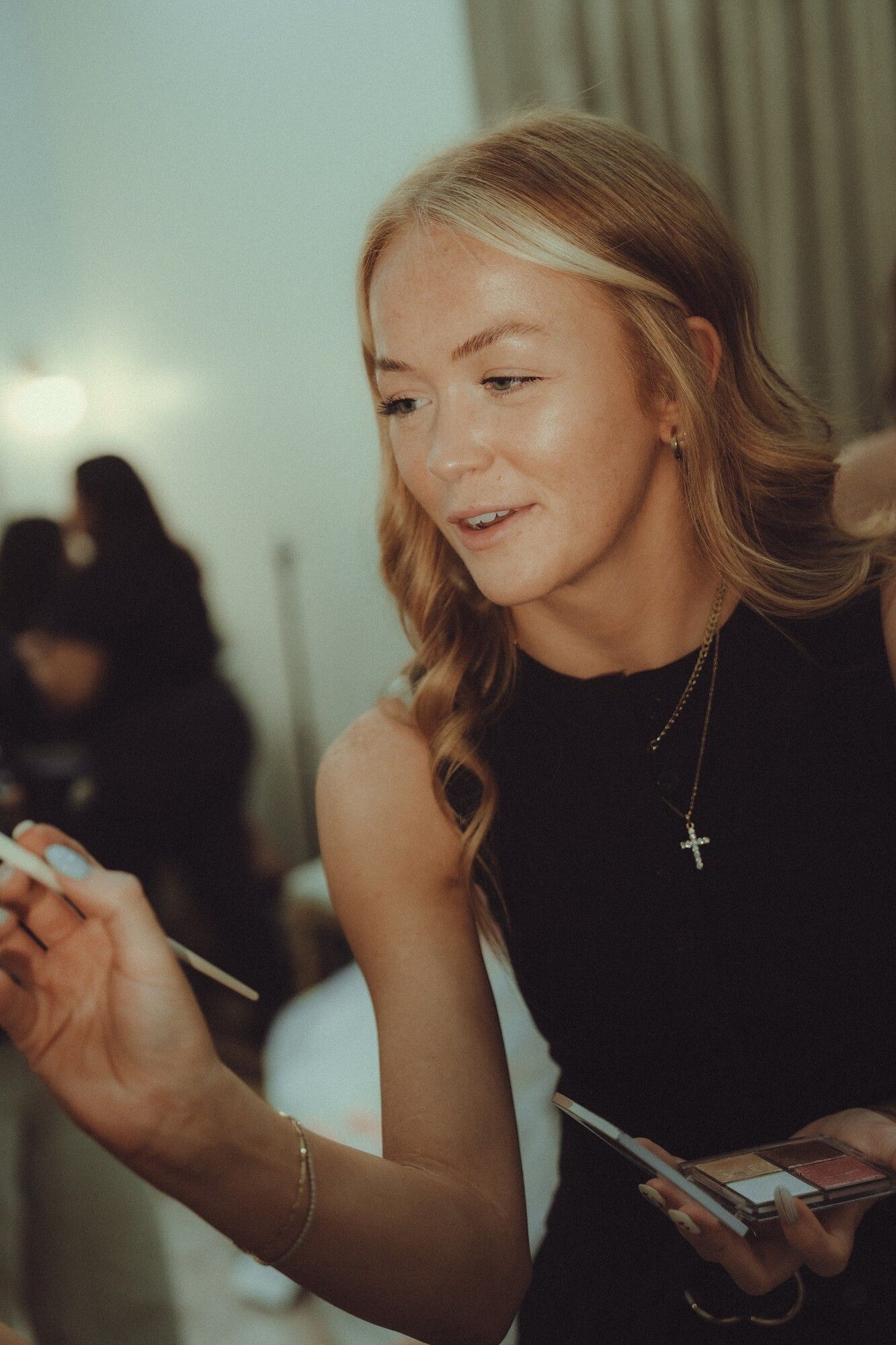 Brynlie smiling down as she mixes makeup on a palette