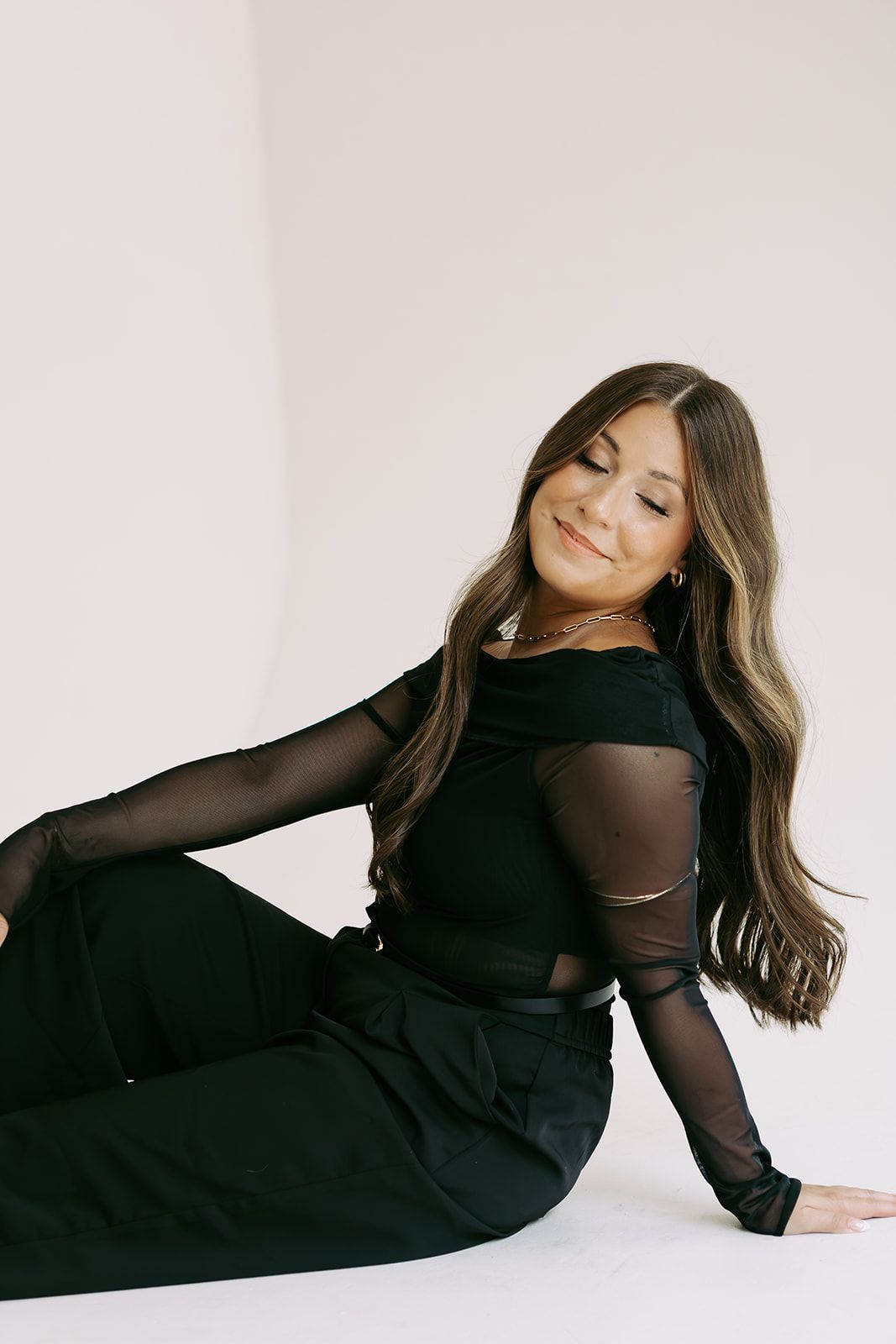 Cady, cofounder and lead hair stylist, seated in black against a white backdrop