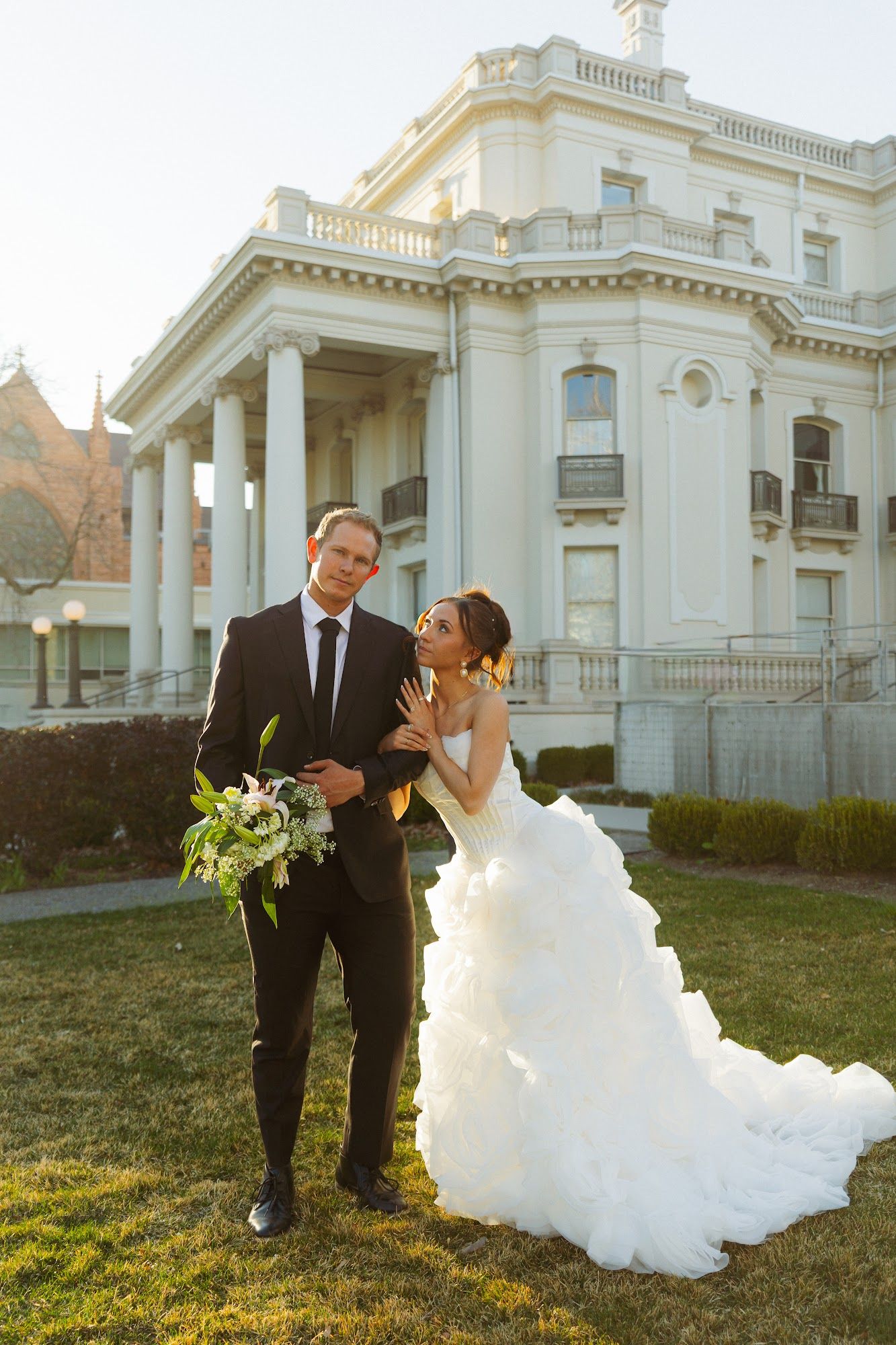 A bride in a ruffled gown and her groom on the lawn of the McCune Mansion in Salt Lake City