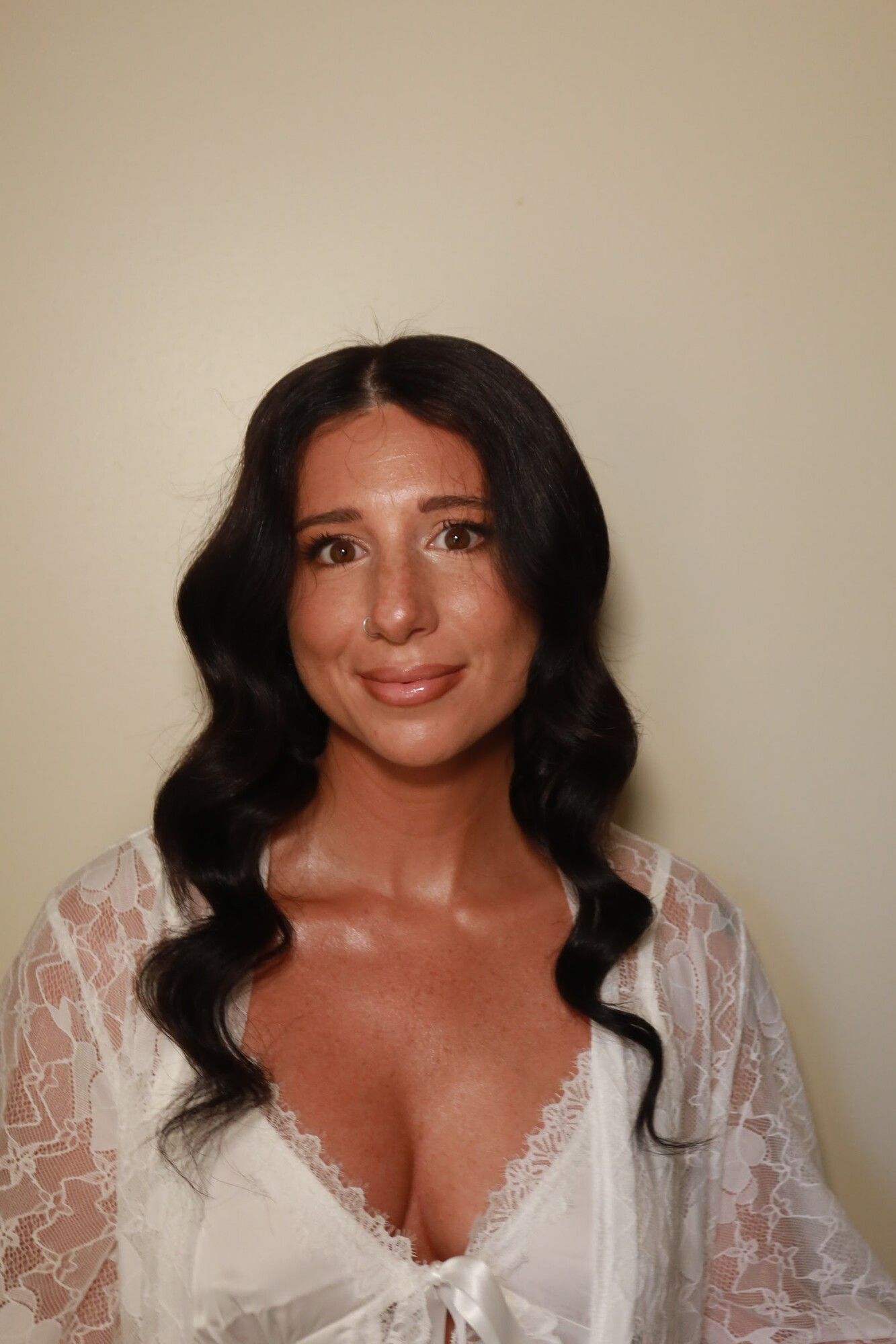 A woman with dark soft waves and glowing soft glam makeup in a lace robe