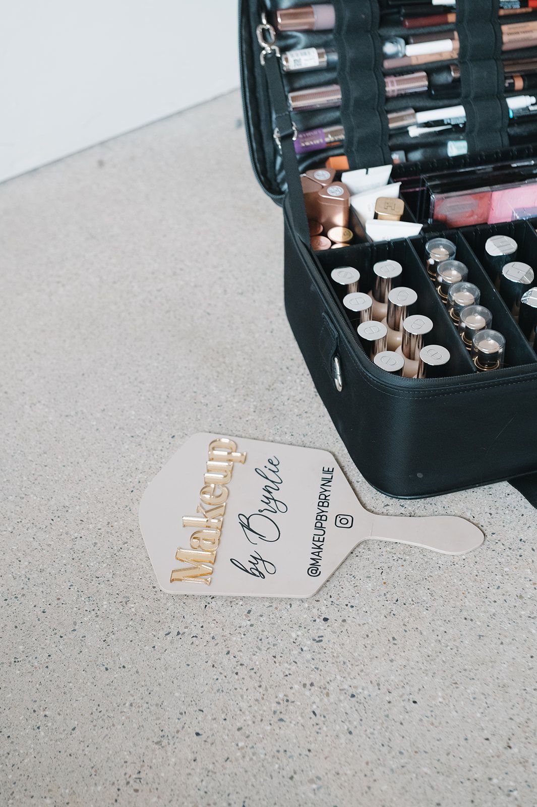Brynlie's open makeup kit beside a hand mirror engraved Makeup by Brynlie