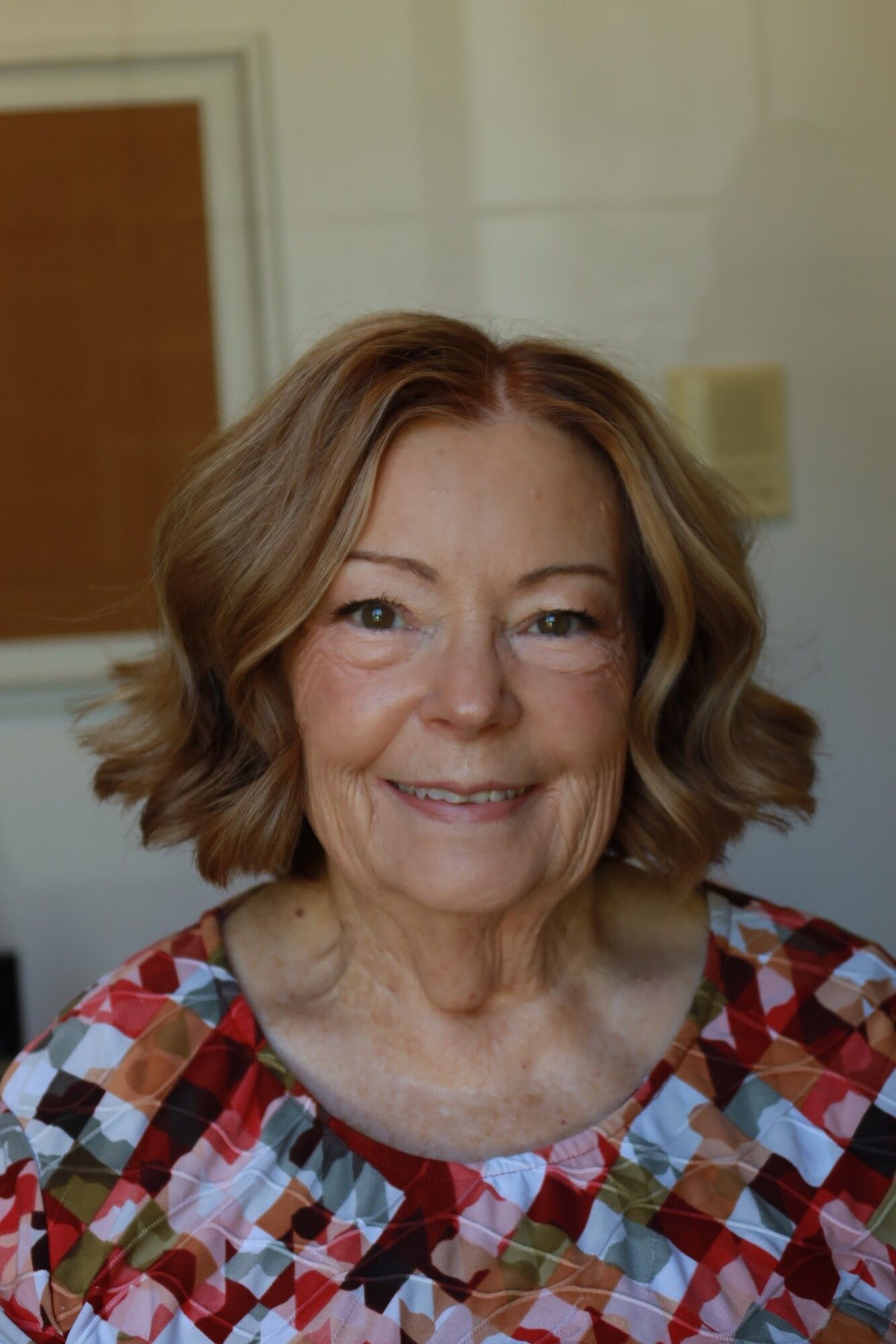 A mother of the bride in a colorful top with soft waves and fresh, natural makeup